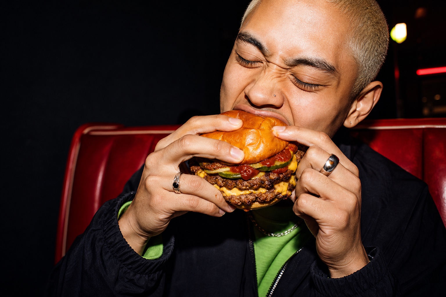 A diner taking a bite of a smashburger in a red booth
